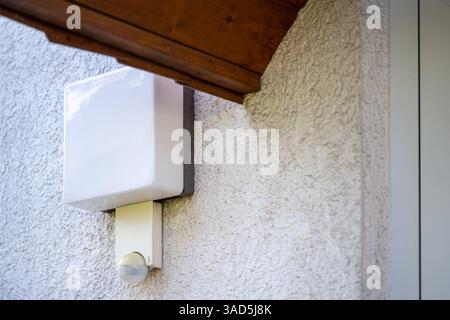 , Deutschland, 05.04.2025,  A rectangular outdoor wall light with integrated motion detector is mounted on the exterior wall of a house, beneath the r Stock Photo