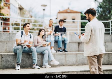 Students engaging in collaborative outdoor learning with helpful professor Stock Photo