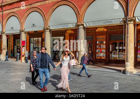 A couple holding hands walking along the elegant porticoes of Via dell'Archiginnasio in Bologna, Italy Stock Photo