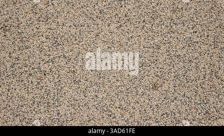 Small stones and pebbles embedded in concrete create a rough, textured surface, ideal for backgrounds and construction projects Stock Photo