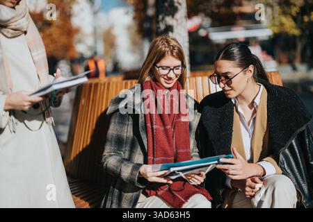 Group of young women collaborating on documents outdoors in autumn Stock Photo