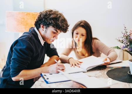 Focused college students studying together at home with textbooks Stock Photo