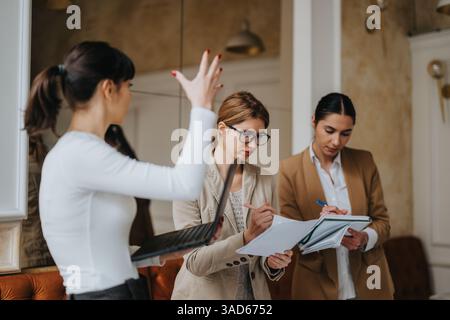 Three businesswomen collaborating on documents and ideas during a team meeting Stock Photo