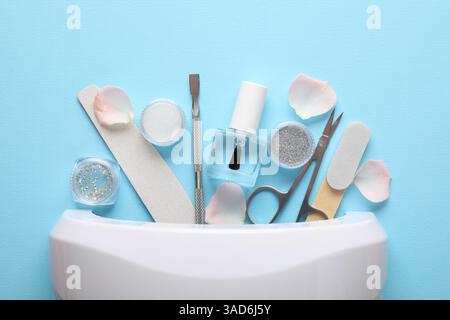 Set of different manicure tools and UV lamp on light blue background, flat lay Stock Photo