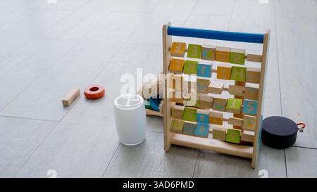 Colorful wooden alphabet and number learning toy with educational blocks, scattered kids toys, and teddy bear on wooden floor in a bright indoor space Stock Photo
