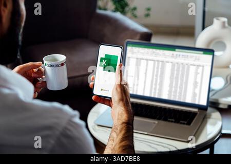 Man using a mobile phone displaying logo of Microsoft Excel on the screen. Spreadsheet software for calculate, formulas and productivity. Stock Photo