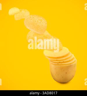 Raw potato slices transforming into crispy chips in air on orange background Stock Photo
