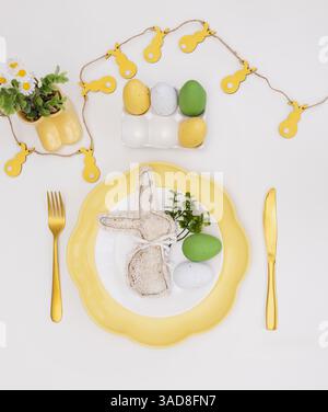 Happy Easter. Easter celebration concept. Top view vertical empty white, yellow plate, decorative rabbit, eggs, isolated white background. Copy space, Stock Photo