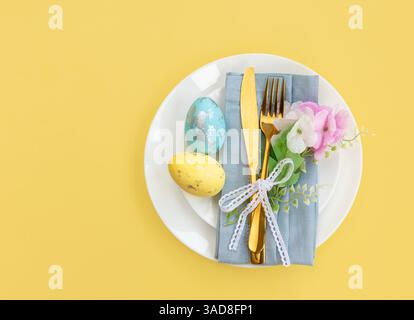 Happy Easter. Easter celebration concept. Top view vertical Napkin empty white and yellow plate, Easter eggs, on isolated yellow background. Copy spac Stock Photo