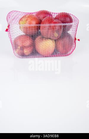 Plastic container of nectarines covered with red mesh in supermarket. Fresh juicy nectarines in plastic package to sell at farmer market isolated on w Stock Photo