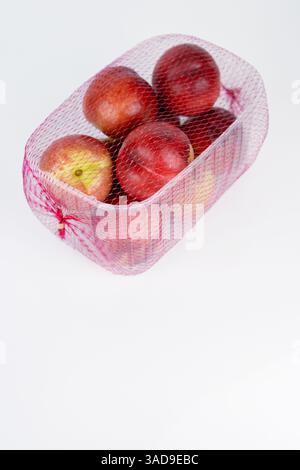Plastic container of nectarines covered with red mesh in supermarket. Fresh juicy nectarines in plastic package to sell at farmer market isolated on w Stock Photo