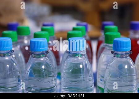 Many blue, green drinking water and refreshment beverage bottle caps and pure drinking water bottles in a drinking water production plant or supermark Stock Photo