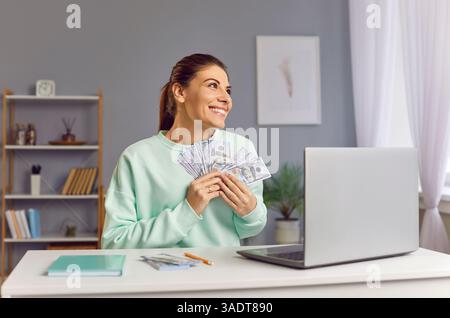 Happy smiling woman holding stack of cash money, celebrating winning lottery or business success. Stock Photo
