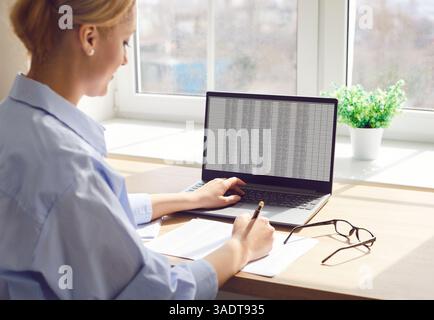 Professional female accountant at her workplace is analyzing financial data in spreadsheet on laptop Stock Photo