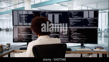 Tech-Savvy Engineer Debugging Software Code on Multiple Computer Screens Stock Photo