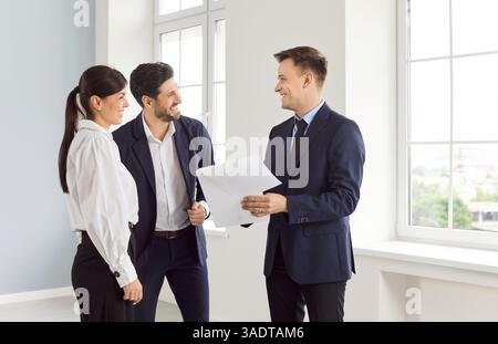 Man and woman talking with man realtor in new house and ready to become homeowners. Stock Photo