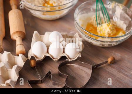 Children whisking flour and eggs in glass bowls while baking cookies together in a warm, rustic kitchen setting. Stock Photo