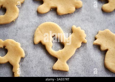 Animal shaped Linzer Easter cookies cut out from raw pastry dough on a baking sheet, closeup Stock Photo