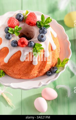 Glazed ring cake for Easter on holiday table with decorations. Easter treat and holiday decorations. Stock Photo