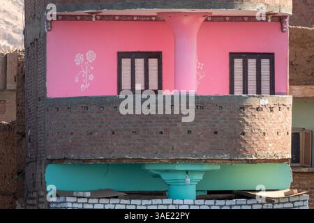A narrow apartment block showing two stacked balconies, one decorated and painted pink with floral motif, the other pale turquoise Stock Photo