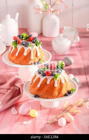 Sweet Easter ring cake on holiday table with decorations. Easter spring background with flowers and easter eggs. Stock Photo