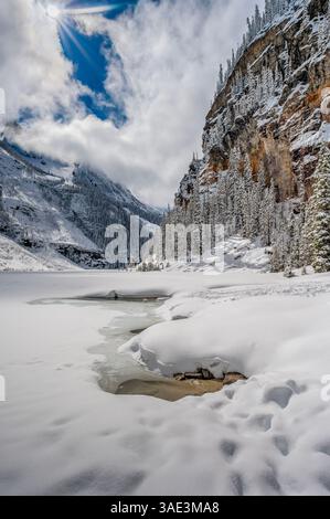 Winter view frozen Lake Louise and sun breaking through clouds in Banff National Park, Alberta, Canada Stock Photo