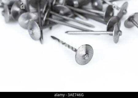 A pile of roofing nails on a white background is an essential metal hardware for construction and repair work. Stock Photo