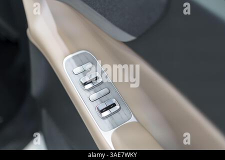 sleek door panel featuring metallic window switches and a wood-textured finish on beige trim, exemplifying premium automotive comfort and style. Stock Photo