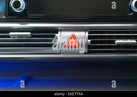 Close-up of a hazard warning button on a car's dashboard vent, emphasizing safety, sleek design, and user-friendly control in a modern vehicle. Stock Photo