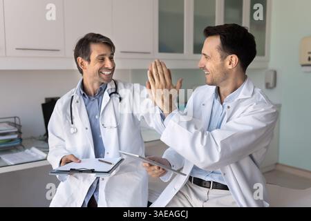 Two middle-aged friendly medical workers colleagues give high five Stock Photo