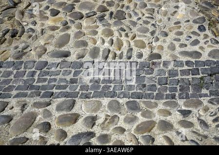 Cobblestone road. Old road paved with stones. Close-up. Copy space. Selective focus. Stock Photo