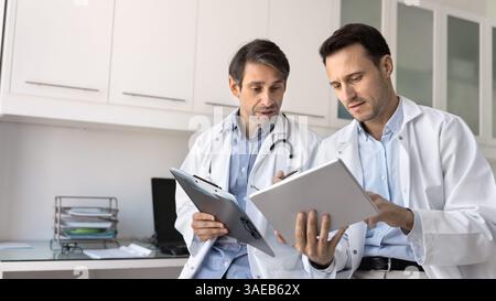 Two serious cardiologists engaged in discussion in modern consulting room Stock Photo