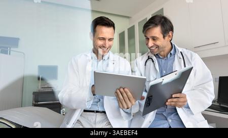 Two smiling male doctors in coats using digital tablet Stock Photo