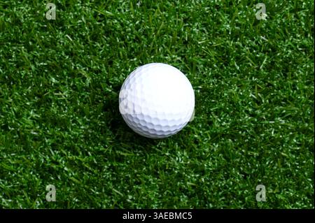 Golf ball on artificial turf, close up. Single, white American golf ball with special notches, on a flat plastic grass surface. Stock Photo