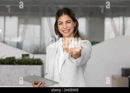 Positive successful Latin business woman lending arm at camera Stock Photo