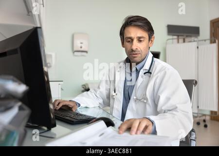 Male doctor in coat reviewing medical documents Stock Photo