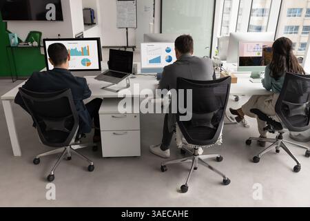 Back view of business colleagues sitting at workplaces, analyzing reports Stock Photo