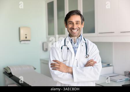 Cheerful doctor in uniform standing confidently in consulting room Stock Photo