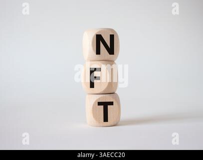NFT - non-fungible token symbol. Concept word NFT on wooden cubes. Beautiful white background. Business and NFT concept. Copy space. Stock Photo
