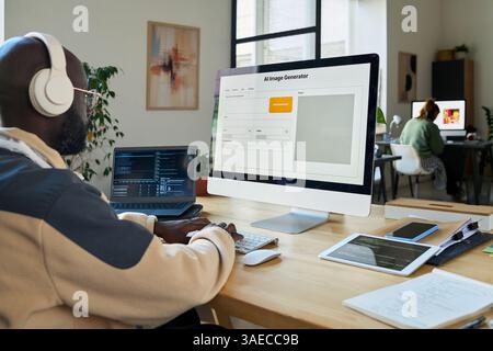 Young African American software developer testing AI image generation program on desktop computer and laptop Stock Photo