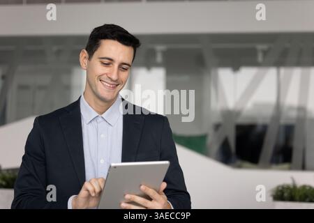 Happy Hispanic businessman working on online startup project with tablet Stock Photo