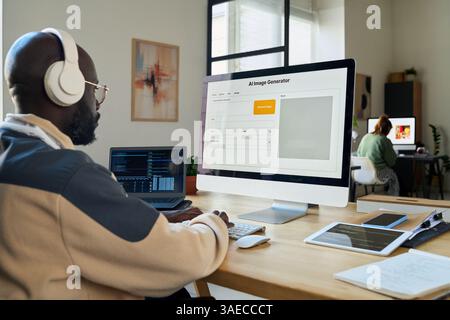 Side view of young businessman typing on computer keypad and using AI image generator while creating new content Stock Photo