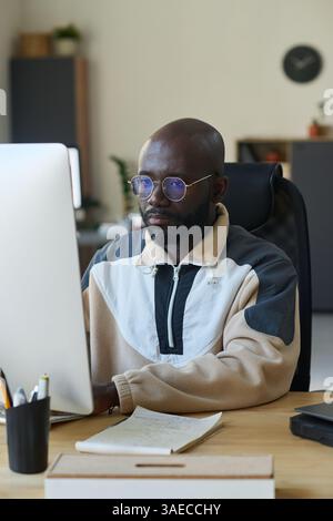 African American male software developer working over new product while sitting in front of computer monitor and looking at screen Stock Photo