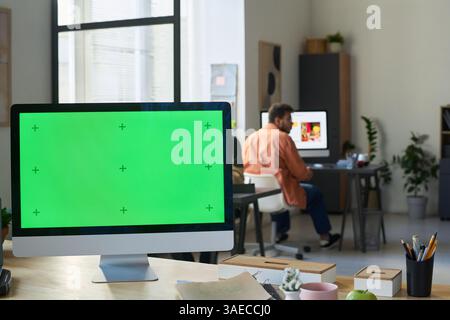 Desktop computer with blank chromakey screen standing on workplace of software developer or programmer in modern office Stock Photo