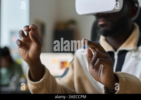 Hands of young African American male employee in VR headset pointing at virtual screen while looking through information Stock Photo
