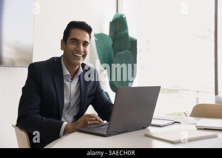 Portrait of Indian businessman sit at desk working on laptop Stock Photo