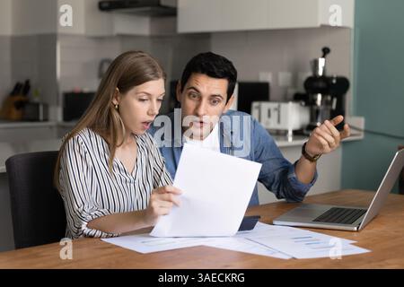 Couple analyzing financial documents with surprised or concerned expressions Stock Photo