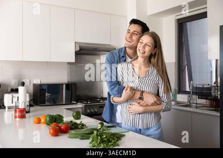 Dreamy couple hugging standing together in modern kitchen Stock Photo
