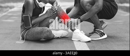 Trauma During Training. African Woman Having Sprained Ankle After Jogging, BW Shot Stock Photo