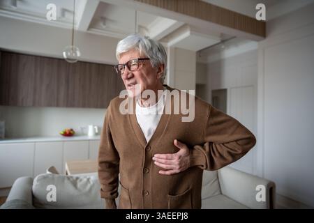 Heart attack. Suffering old man clutches chest with pained expression while struggling to breathe Stock Photo